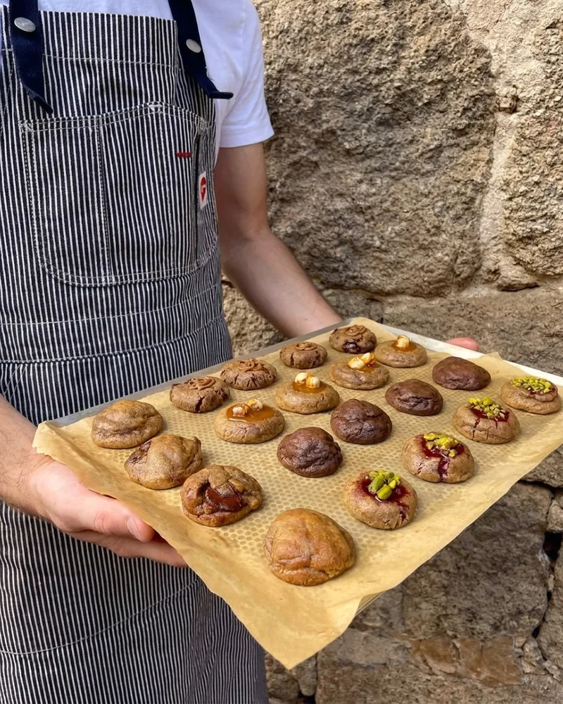 Une plaque de cookies Gramme, tenue devant un mur de granit